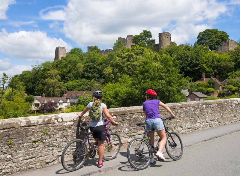 Two cyclists admiring the view of Ludlow from Dinham Bridge, Shropshire.